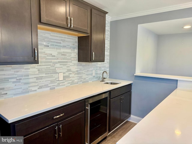 kitchen with beverage cooler, tasteful backsplash, light countertops, dark brown cabinets, and a sink