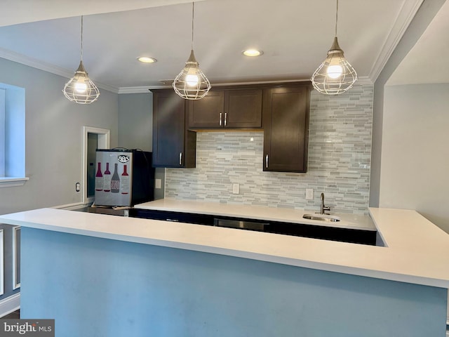 kitchen with decorative backsplash, crown molding, dark brown cabinets, fridge, and a sink