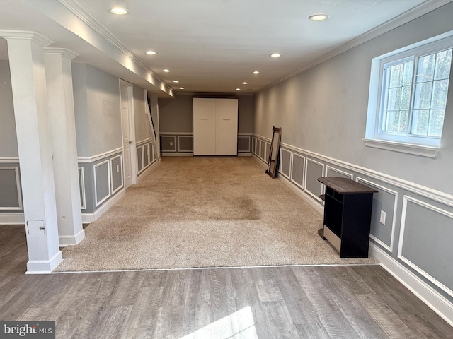 interior space featuring ornamental molding, a decorative wall, wood finished floors, and recessed lighting