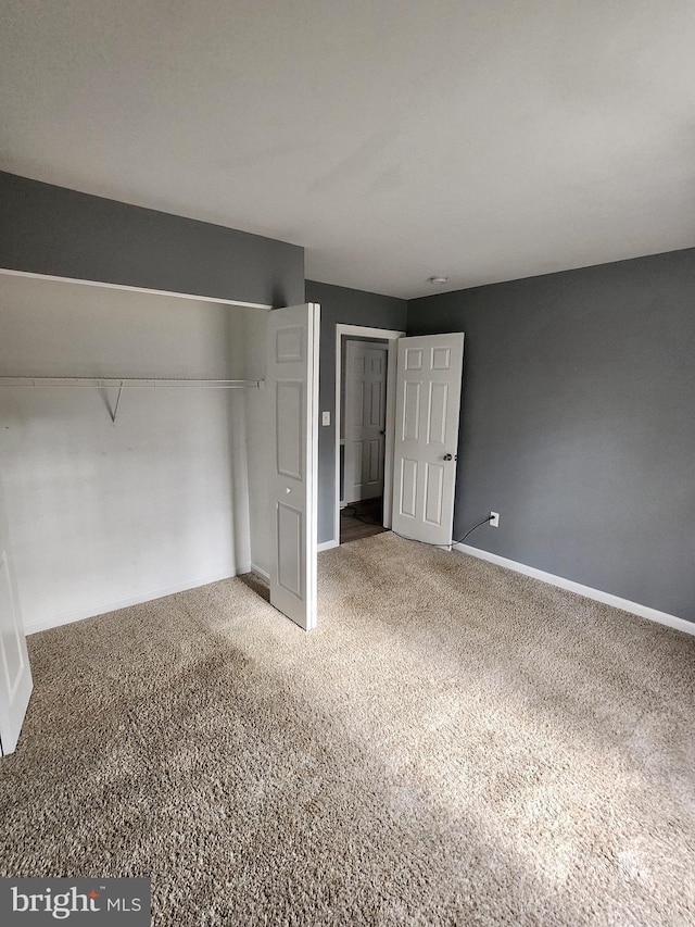 unfurnished bedroom featuring carpet, a closet, and baseboards