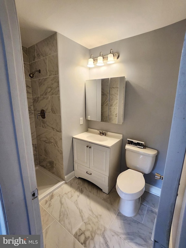 full bath featuring marble finish floor, tiled shower, and baseboards