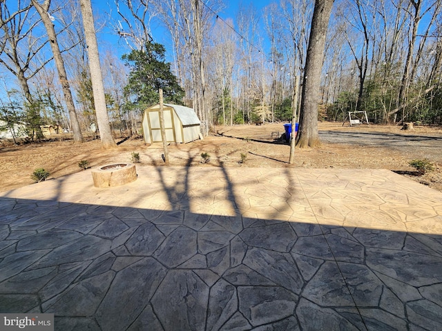 view of yard featuring a fire pit, a shed, a patio area, and an outbuilding