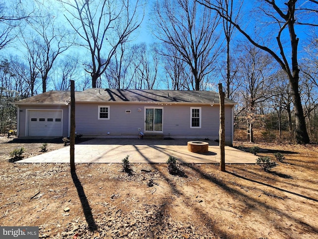 rear view of house with an attached garage, an outdoor fire pit, and a patio area