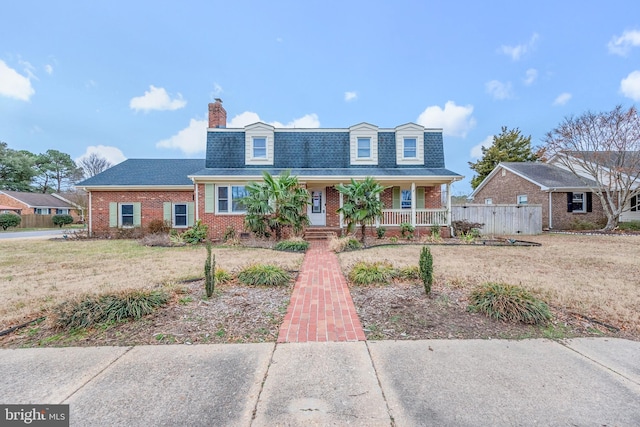 new england style home with a front yard and covered porch