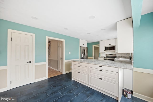 kitchen featuring sink, white cabinets, stainless steel appliances, light stone countertops, and backsplash