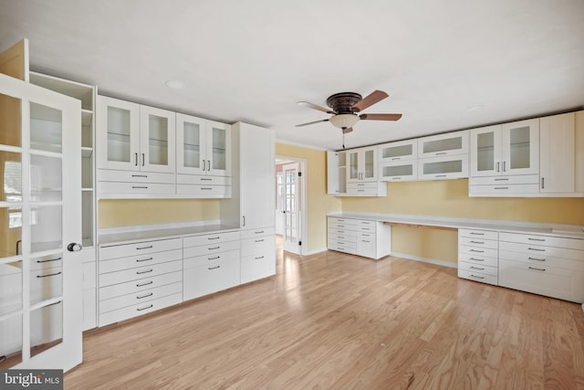 kitchen featuring ceiling fan, built in desk, light hardwood / wood-style flooring, and white cabinets