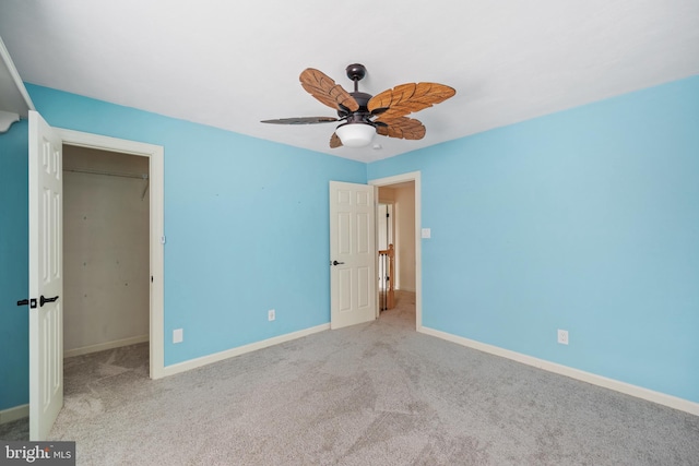 unfurnished bedroom with ceiling fan, light colored carpet, a closet, and a walk in closet