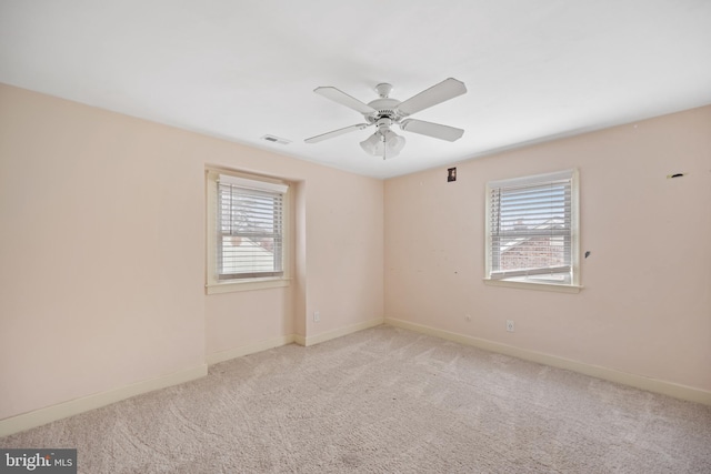 carpeted spare room featuring ceiling fan and a healthy amount of sunlight