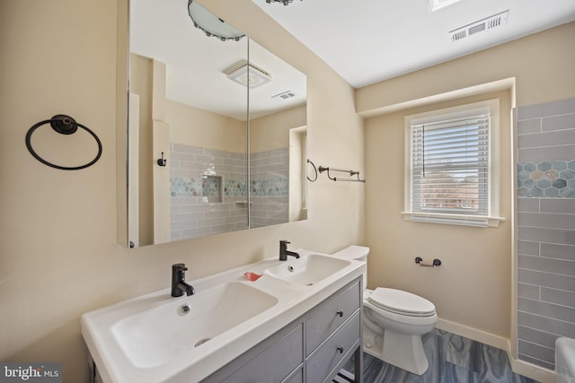 bathroom featuring vanity, toilet, and tiled shower