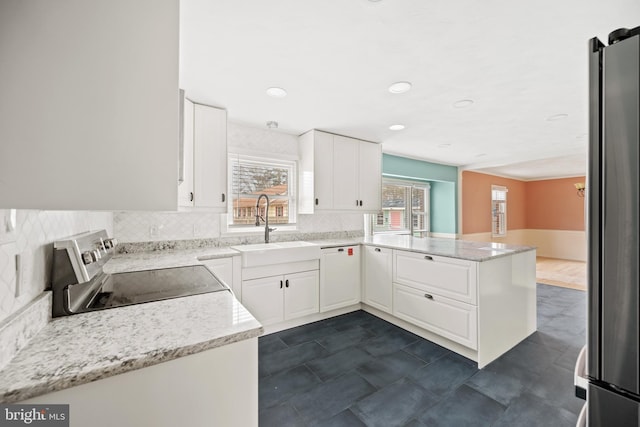 kitchen with white cabinetry, sink, stainless steel appliances, and kitchen peninsula