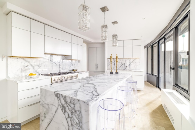 kitchen featuring a large island, white cabinetry, hanging light fixtures, an inviting chandelier, and stainless steel gas stovetop