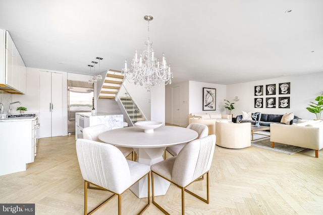 dining area with an inviting chandelier, sink, and light parquet flooring