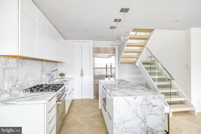 kitchen featuring sink, white cabinets, premium appliances, hanging light fixtures, and light parquet floors