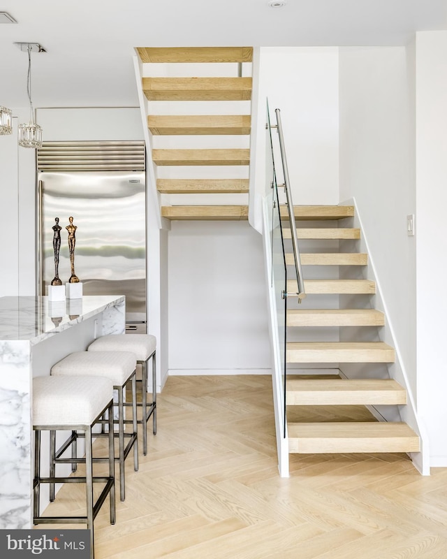 stairway featuring parquet flooring