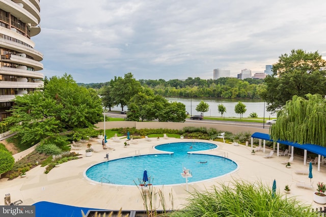 view of swimming pool featuring a water view and a patio