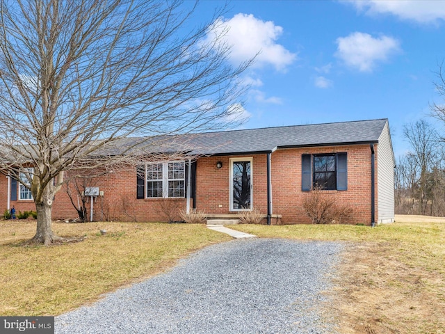 single story home with brick siding, a shingled roof, and a front yard