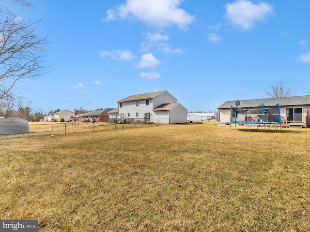 view of yard featuring a trampoline and fence