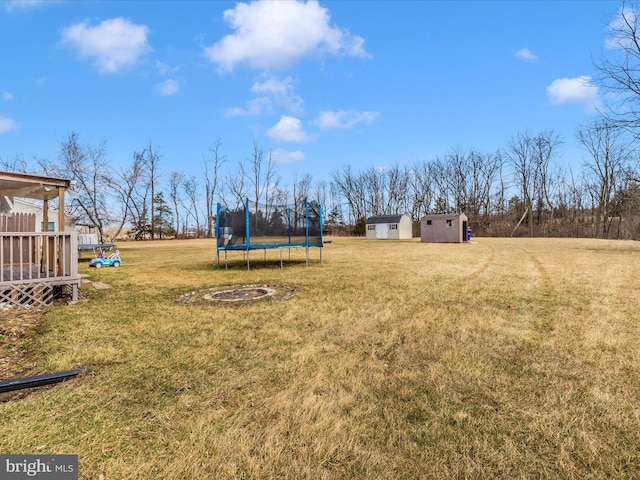 view of yard with a trampoline and an outbuilding