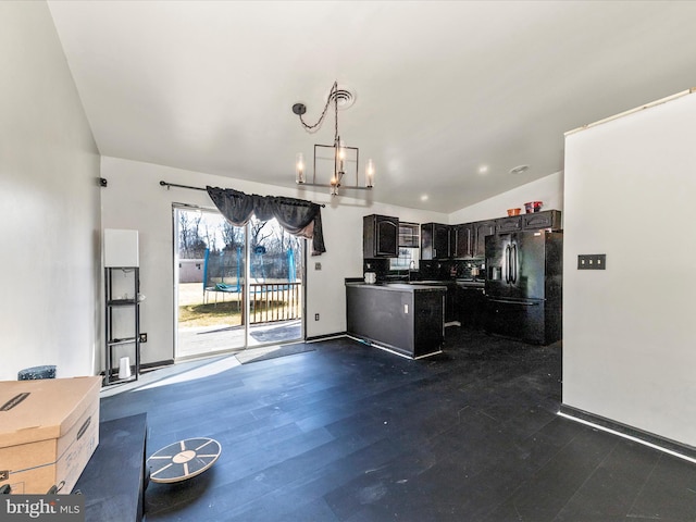 kitchen with lofted ceiling, an inviting chandelier, black refrigerator with ice dispenser, dark cabinetry, and a sink