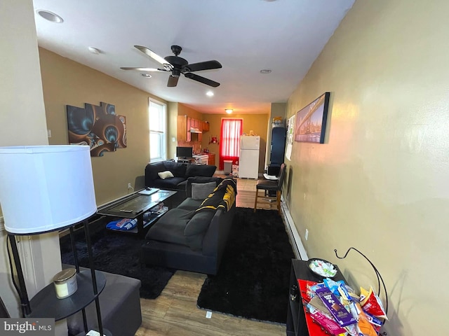 living room featuring baseboard heating, ceiling fan, and light hardwood / wood-style floors