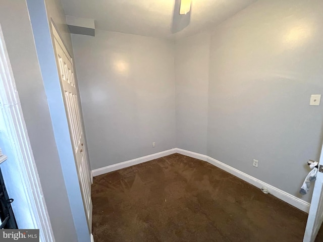 empty room featuring ceiling fan and dark colored carpet