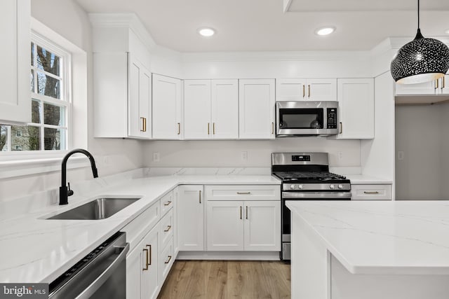 kitchen with decorative light fixtures, sink, white cabinets, stainless steel appliances, and light stone countertops