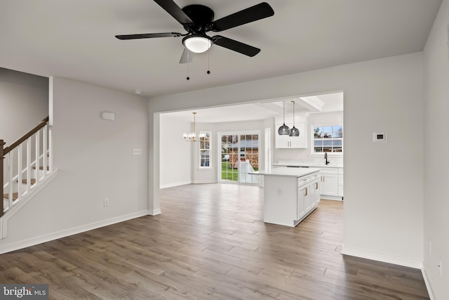 unfurnished living room featuring ceiling fan with notable chandelier, sink, and light hardwood / wood-style floors