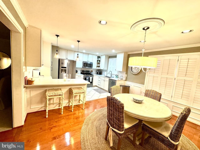 dining area with sink, crown molding, and light wood-type flooring