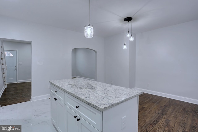 kitchen with decorative light fixtures, white cabinetry, a center island, light stone counters, and dark wood-type flooring