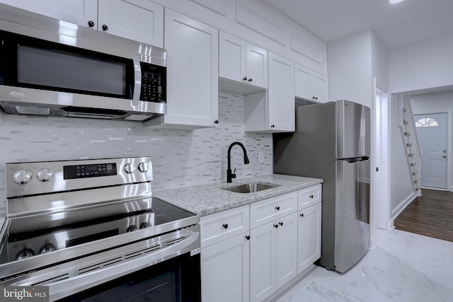 kitchen featuring light stone countertops, white cabinetry, appliances with stainless steel finishes, and sink