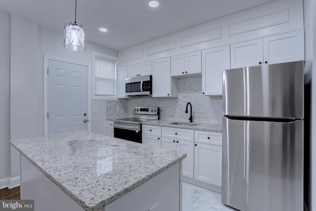 kitchen with sink, stainless steel appliances, a center island, and white cabinets