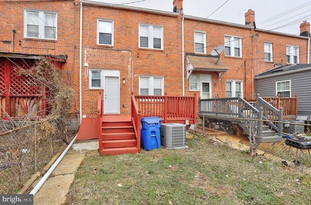 rear view of property featuring a wooden deck, a yard, and central AC