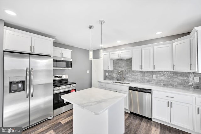 kitchen with sink, appliances with stainless steel finishes, dark hardwood / wood-style floors, pendant lighting, and white cabinets