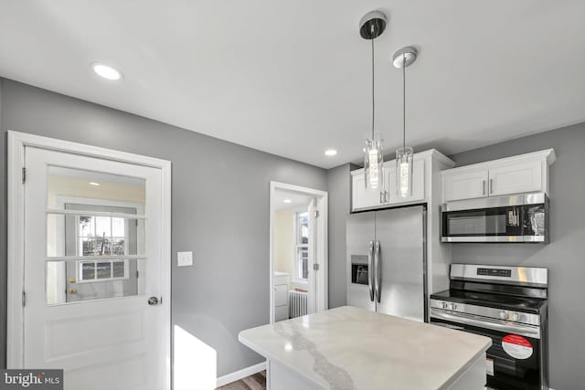 kitchen with white cabinetry, stainless steel appliances, radiator, and pendant lighting