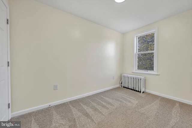 spare room with radiator heating unit and light colored carpet