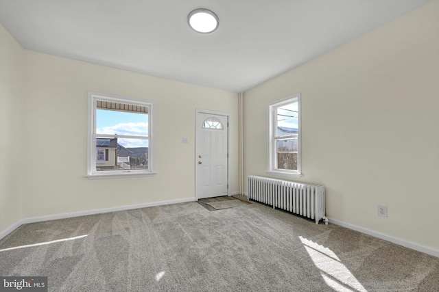 carpeted entrance foyer featuring radiator heating unit and a wealth of natural light