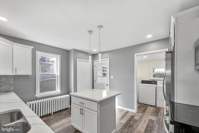 kitchen featuring separate washer and dryer, dark hardwood / wood-style floors, radiator heating unit, and white cabinets