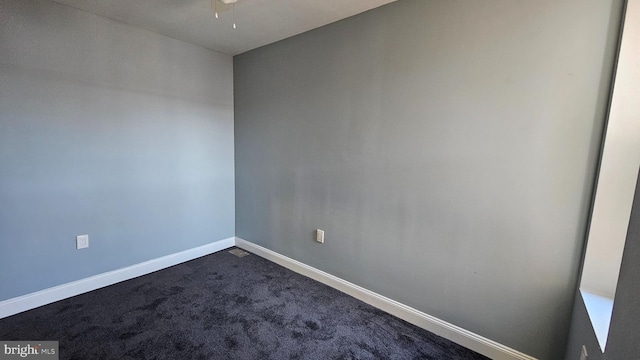 empty room featuring ceiling fan and dark colored carpet