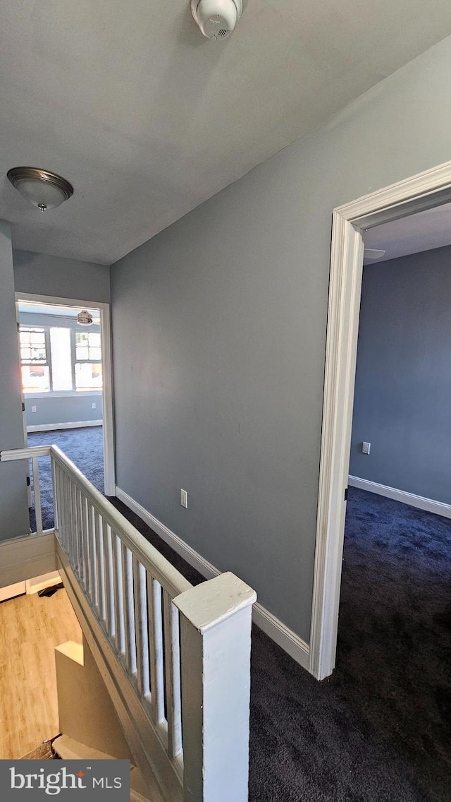 hall featuring dark colored carpet