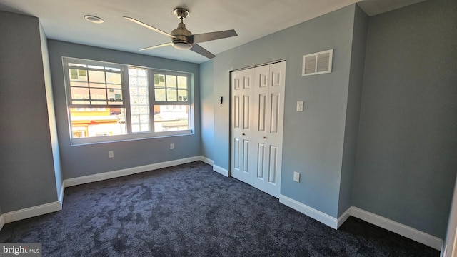 unfurnished bedroom with dark carpet, a closet, and ceiling fan