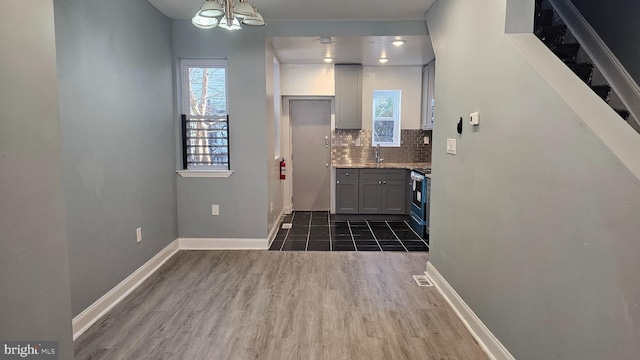 kitchen with sink, gray cabinets, backsplash, stainless steel range oven, and dark hardwood / wood-style flooring