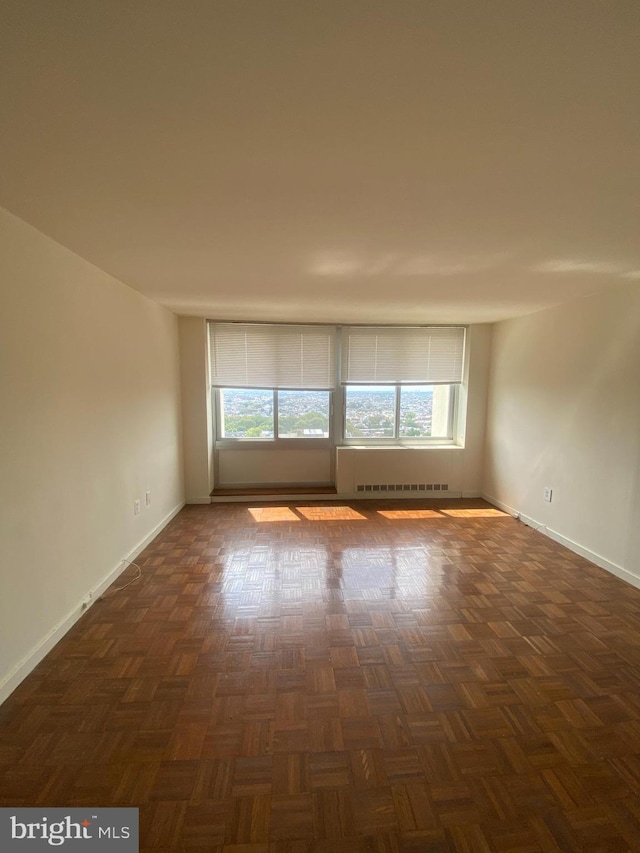 spare room with dark parquet flooring and radiator heating unit