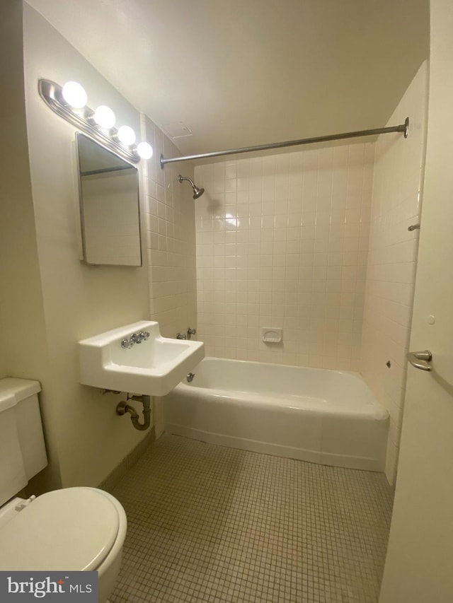 full bathroom with tile patterned floors, toilet, tiled shower / bath combo, and sink