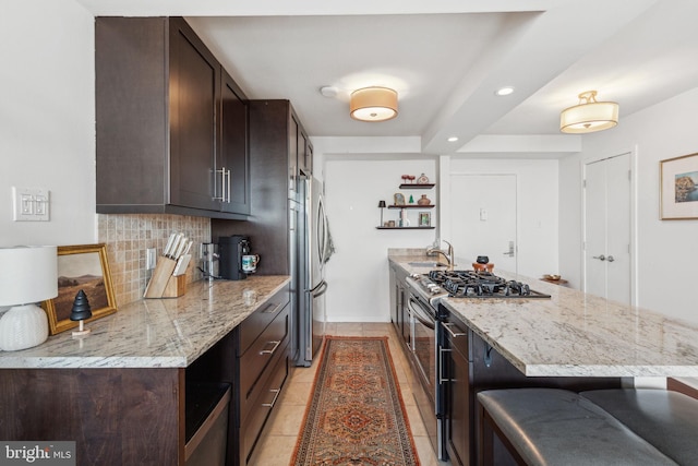 kitchen with light stone counters, stainless steel appliances, sink, and decorative backsplash