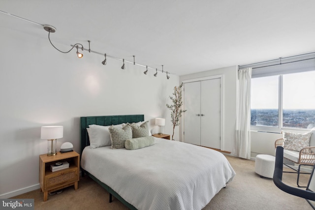 carpeted bedroom featuring rail lighting and a closet