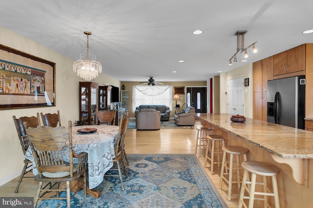 dining space featuring ceiling fan with notable chandelier, rail lighting, and light wood-type flooring