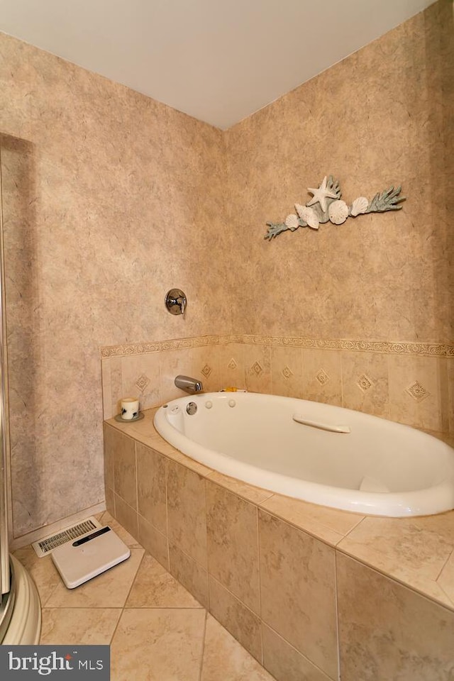 bathroom with tiled bath, tile patterned flooring, and tile walls