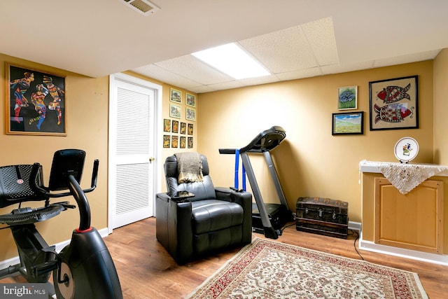 exercise room featuring hardwood / wood-style flooring and a drop ceiling