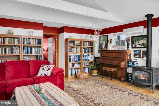 sitting room featuring vaulted ceiling, a wood stove, hardwood / wood-style floors, and a wall unit AC