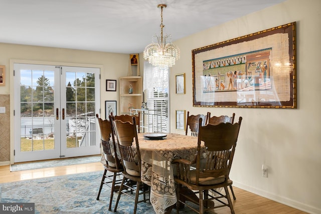 dining room with hardwood / wood-style floors, a chandelier, and french doors